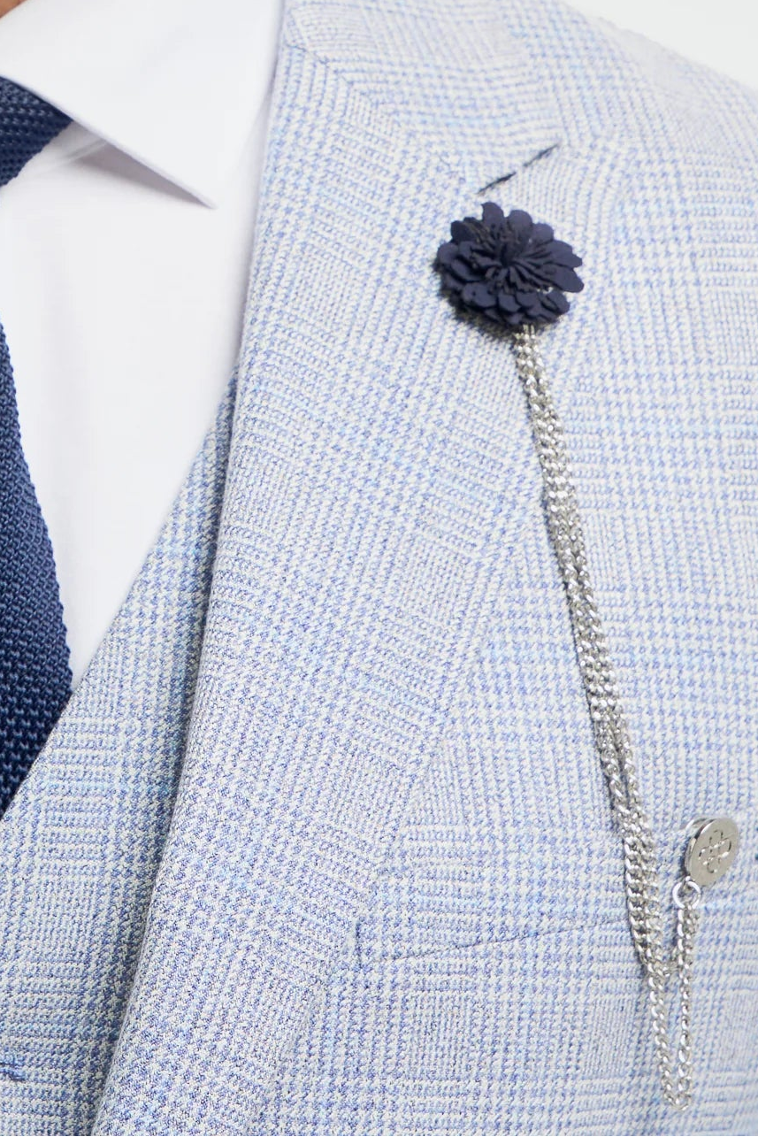 Mann in hellgrauem Anzug mit marineblauer Krawatte und Blumenbrosche vor weißem Hintergrund