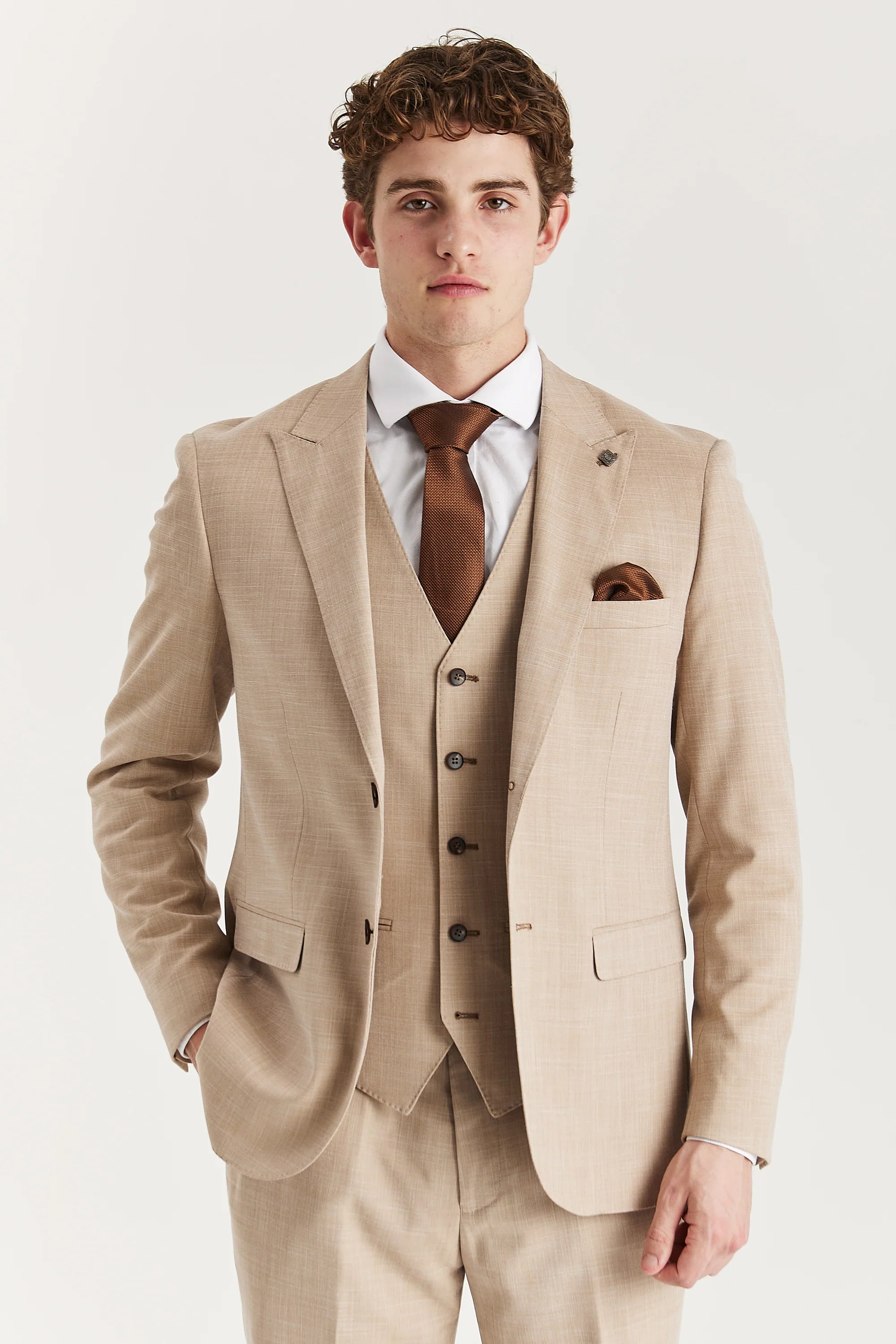 Man wearing a beige suit with a brown tie on a white background